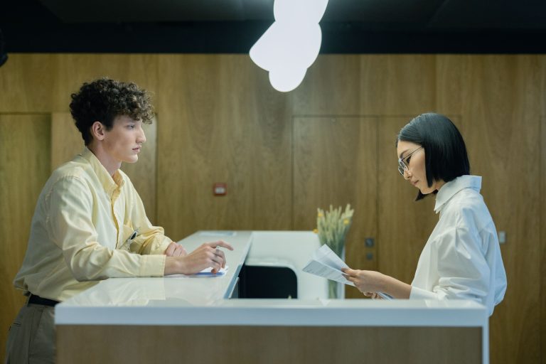 Service counter staff helping a visitor with documents