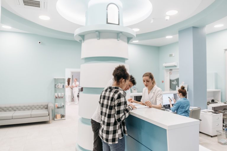 Patients at a clinic reception desk with staff.