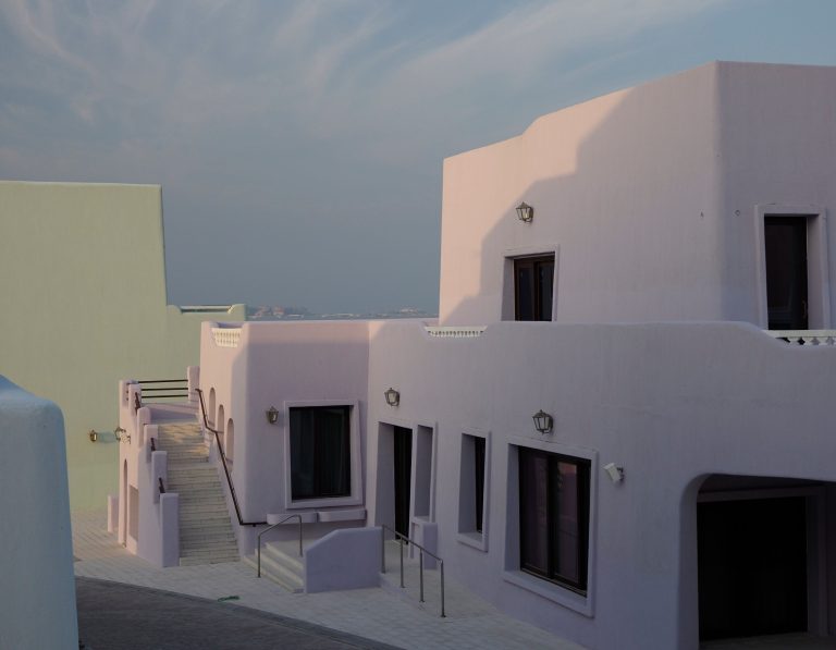 Low-rise residential buildings in pastel colours in Doha, Qatar, under a pale sky.